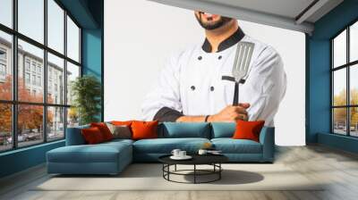 Smiling Asian Indian happy chef with spatula, standing against white background Wall mural