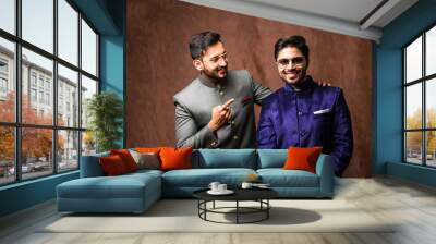 two Indian men wears ethnic or traditional cloths,  Male fashion models with sherwani or Kurta Pyjama, standing and posing over brown grunge background, selective focus Wall mural