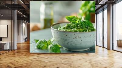 Pesto sauce with a spoon displayed on a kitchen table, offering ample copy space image. Wall mural