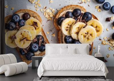 Top view of two slices of toast with banana, blueberries, and chocolate drops on cereal bread for a healthy breakfast or snack with copy space image. Wall mural