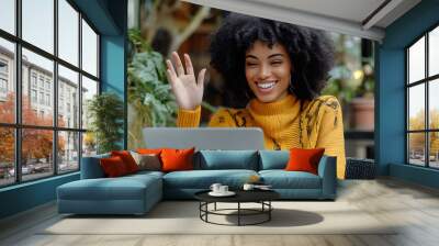 Gen z woman with beautiful natural curls, sitting in a coffee shop and working on her laptop, modern type of work  Wall mural