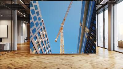 A large tower crane in the downtown of the modern city. Glass office buildings around. Low angle wide shot Wall mural