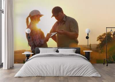 Farmers man and woman communicate in the field at sunset. Use a tablet Wall mural