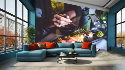 Man eating sushi set with chopsticks on restaurant Wall mural