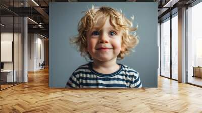 Portrait of a cute little boy with blond curly hair and blue eyes Wall mural