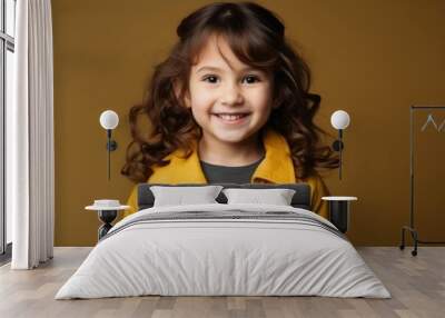 Portrait of a cute little girl in yellow jacket over brown background Wall mural