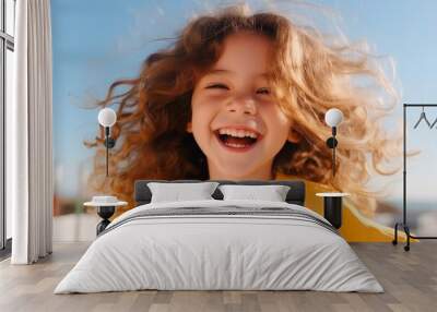 Portrait of a cute little girl with long curly hair on the beach Wall mural