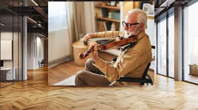 Elderly man in the wheelchair playing the violin at home Wall mural