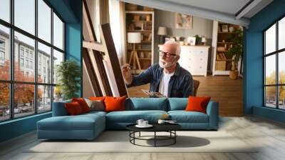 Elderly man painting on a canvas at home Wall mural