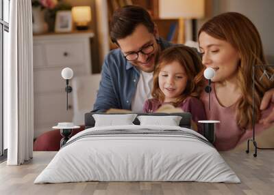 Family with little daughter reading book on sofa in living room Wall mural