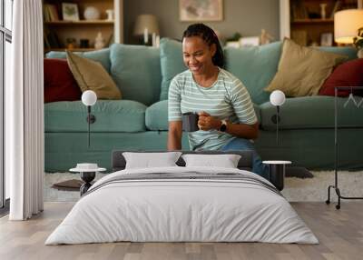 Happy african american woman with laptop at home Wall mural