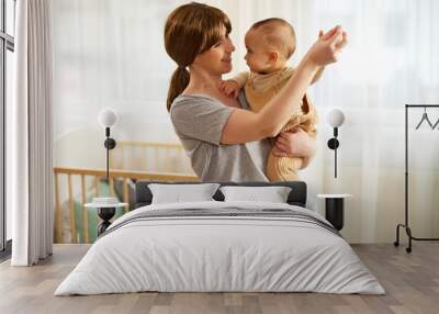 Happy mother enjoying time with her cute baby boy at home dancing Wall mural