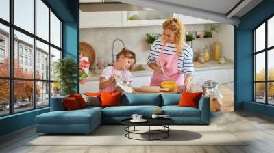 Mother and daughter making cakes together in the kitchen Wall mural