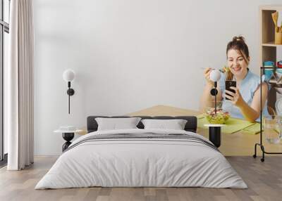 Woman eating salad and connecting with her phone Wall mural