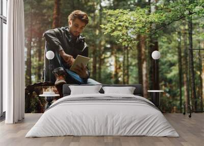 young man using a digital tablet in the woods Wall mural