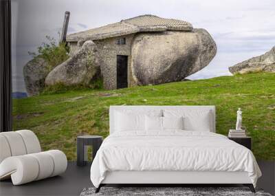 House built between huge rocks on top of a mountain Wall mural