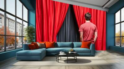 Person in red shirt standing in front of red curtains, peering between them, possibly backstage at a theater or stage event. Wall mural