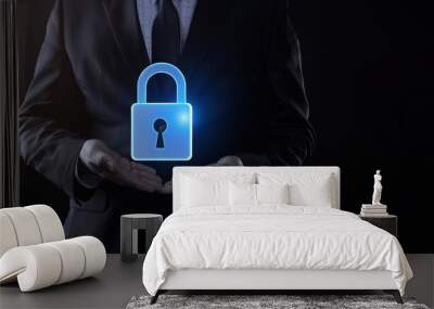 Businessman in suit holding blue glowing padlock icon on black background symbolizing cyber security concept Wall mural