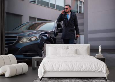 Young handsome business man in a suit comes out of the luxury car Wall mural