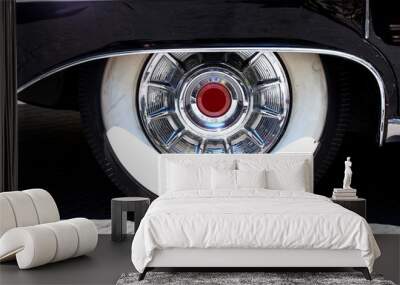 Old car wheel covered by black metallic wing Wall mural