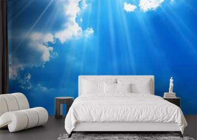 A bright sunny sky with radiant beams of sunlight piercing through fluffy white clouds, representing hope and renewal. Wall mural