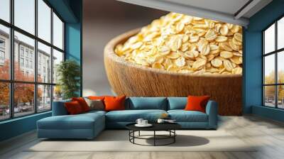 A close-up of rolled oats piled up in a wooden bowl, focusing on the natural texture and wholesome attributes under soft lighting. Wall mural