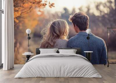 A couple embraces warmly, surrounded by fall foliage's soft light in a tranquil forest setting. Wall mural