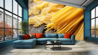 Close-up of various types of uncooked pasta scattered on a rustic wooden surface, showcasing texture and detail. Wall mural