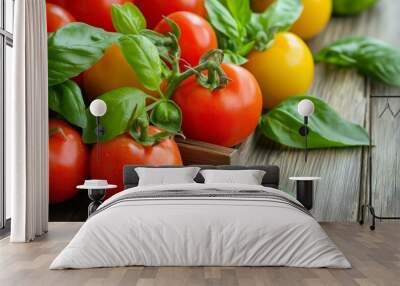 Colorful and fresh assortment of red and yellow tomatoes paired with green basil leaves presented on a wooden surface. Wall mural