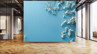 Delicate white flowers are artistically arranged over a soft blue background, creating a serene and peaceful view. Wall mural