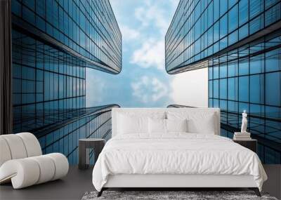 Perspective view looking up between two modern skyscrapers with reflective glass exteriors against a partly cloudy sky. Wall mural