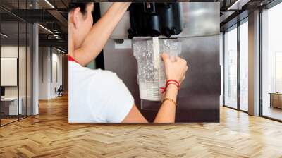 Woman operating machine to pour thick shake Wall mural