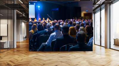 Audience attending a conference with a panel discussion on stage, featuring a blue-lit atmosphere in a modern convention hall. Wall mural