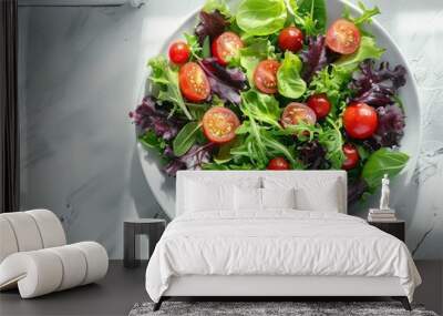 Fresh mixed green salad with cherry tomatoes on a white marble surface, light and healthy summer meal, vibrant colors. Wall mural