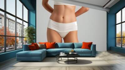 Woman in white underwear, close-up on midsection, showing toned abs and slim waist, isolated on gray background. Wall mural