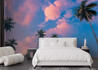 Coconut palm trees in front of a beautiful peaceful blue sky with pink clouds. Wall mural