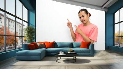 Asian, Indonesian man standing wearing pink shirt pointing right, left, up, down and presenting using hand gestures. Isolated on white background Wall mural