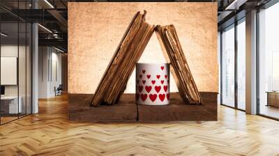 Old books and mug with many pictured hearts on the old wooden ta Wall mural