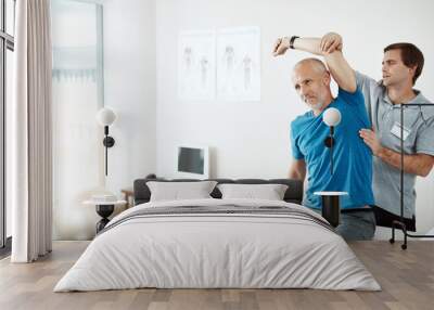 Stretching, physiotherapy and a man with doctor for physical therapy, fitness and health support. Healthcare, sports training and a physiotherapist with a senior patient and arm stretch after injury Wall mural