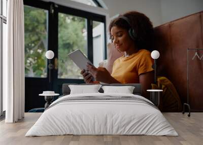 Attractive young black woman using a digital tablet while relaxing at home during corona virus lockdown Wall mural