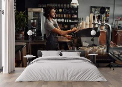 cheerful caucasian coffee shop owner wearing apron preparing coffee using machine Wall mural