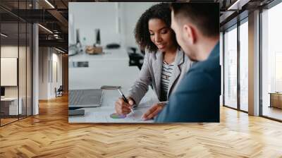 Close-up of young female executive discussing business plan to her colleague with graph and chart on desk Wall mural