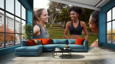 Group of diverse fit and active athletic female friends smiling and having fun together in the park before doing exercise Wall mural