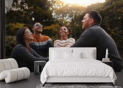 Group of happy multiethnic friends standing together in circle at park stacking their hands Wall mural