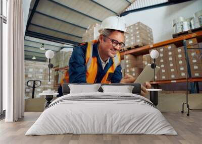 Happy male industrial employee checking digital tablet wearing protective work wear at warehouse Wall mural