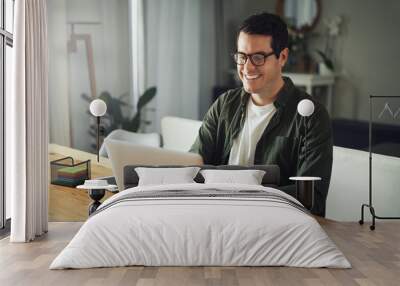 Happy man wearing eyeglasses using laptop at home Wall mural