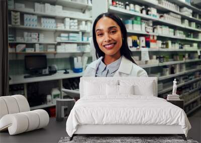 Happy woman working in pharmacy using digital tablet wearing labcoat looking at camera Wall mural