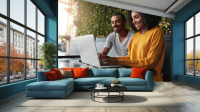 Happy young couple in café looking at laptop Wall mural