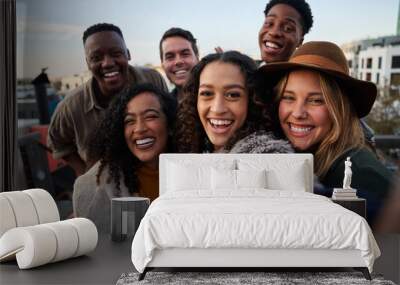 Multi-cultural group of friends taking a selfie at a rooftop party. Close up, smiles with diverse young adults. Wall mural