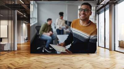 Portrait of a confident male entrepreneur with digital tablet smiling to camera in a working environment Wall mural